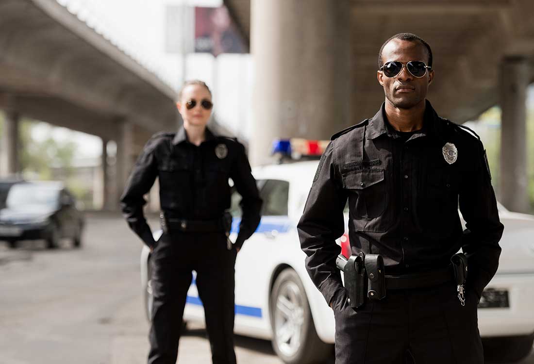 2 police officers standing by a police cruiser