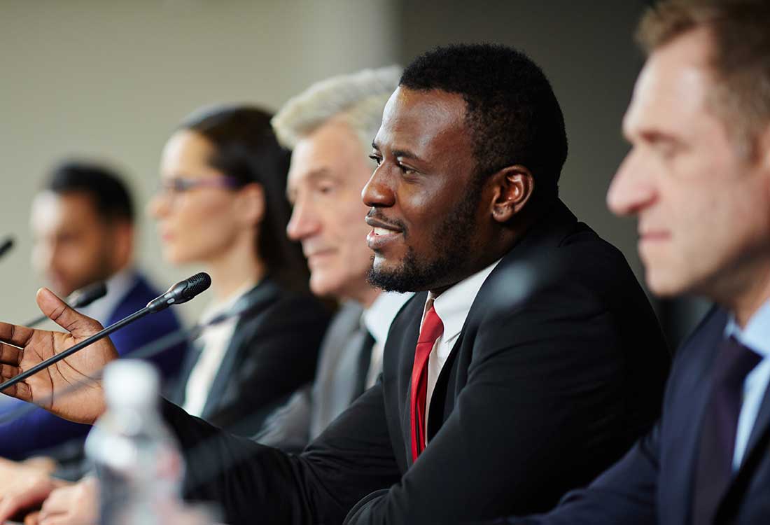 a group of people looking at a man in a suit and tie