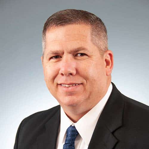 a man wearing a suit and tie smiling at the camera