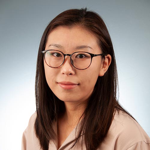 a woman wearing glasses and smiling at the camera