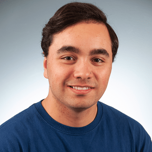a man wearing a blue shirt and smiling at the camera