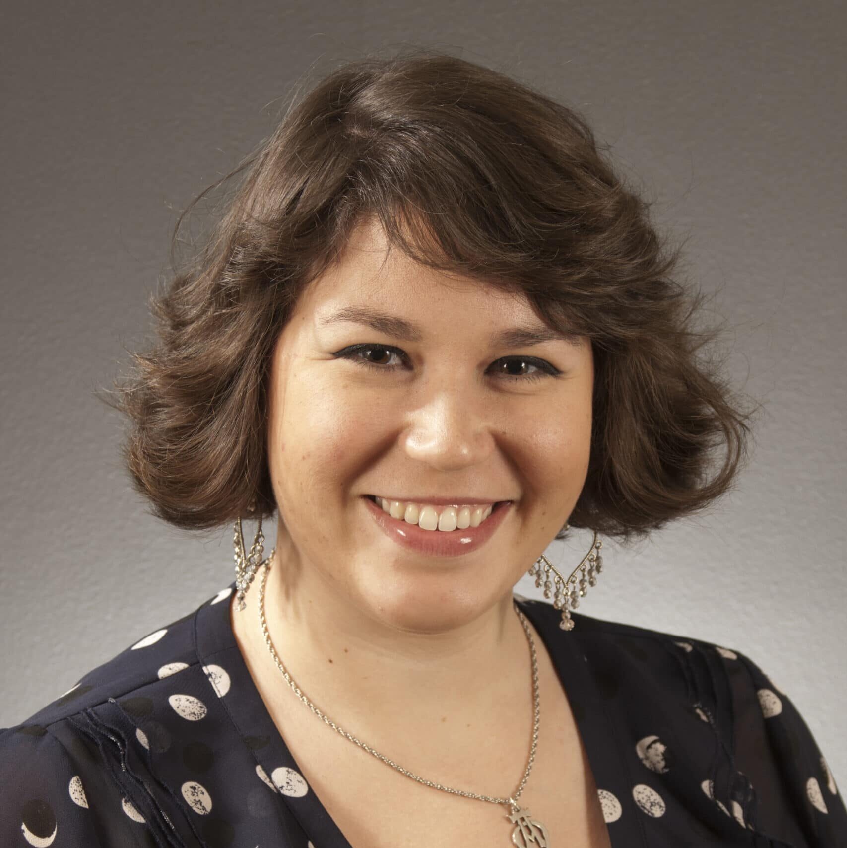 a woman wearing glasses and smiling at the camera