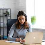 a woman sitting at a table using a laptop computer