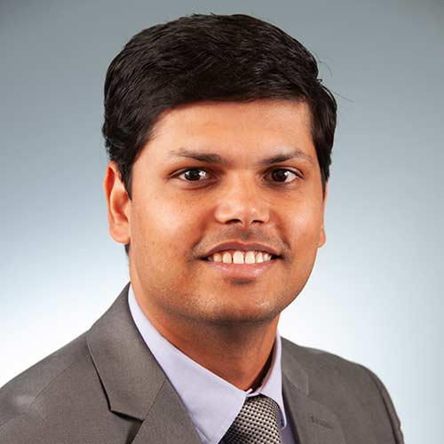 a man wearing a suit and tie smiling at the camera