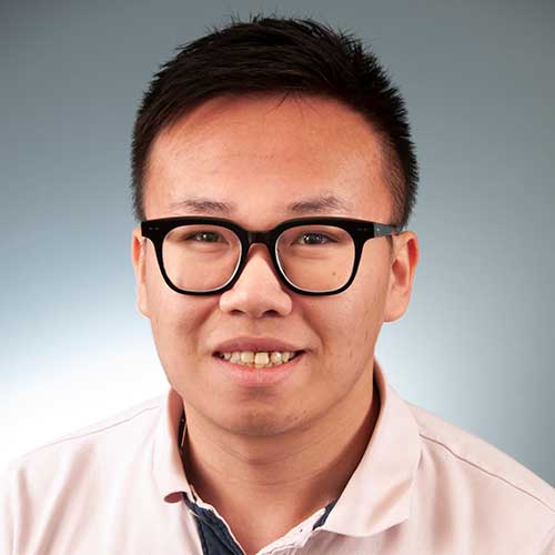 a man wearing glasses and smiling at the camera