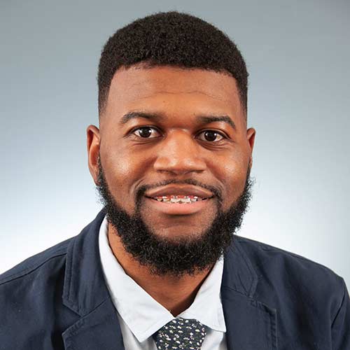 a man wearing a suit and tie smiling at the camera