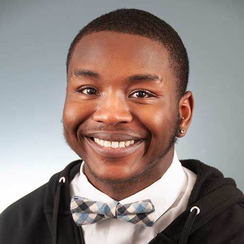 a man wearing a suit and tie smiling at the camera