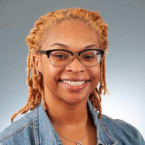 a woman wearing glasses and smiling at the camera