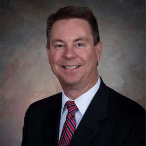 A Man Wearing A Suit And Tie Smiling At The Camera