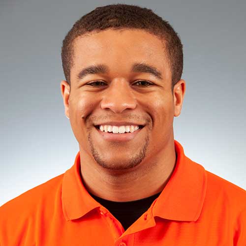 a man wearing an orange shirt and smiling at the camera