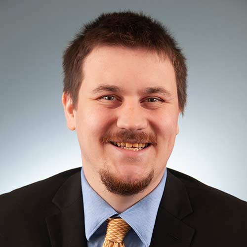 a man wearing a suit and tie smiling at the camera