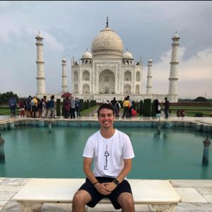Evan Mott sitting on a bench in front of Taj Mahal
