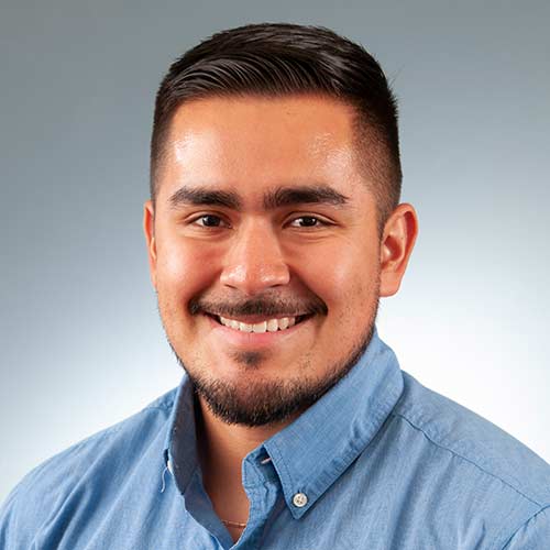 a man wearing a blue shirt and smiling at the camera