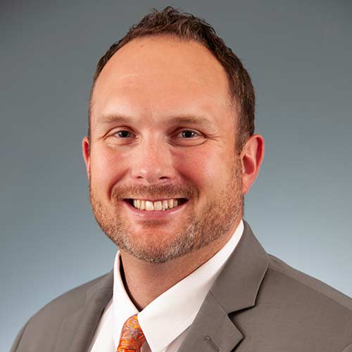 a man wearing a suit and tie smiling at the camera