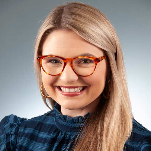 a woman wearing glasses and smiling at the camera