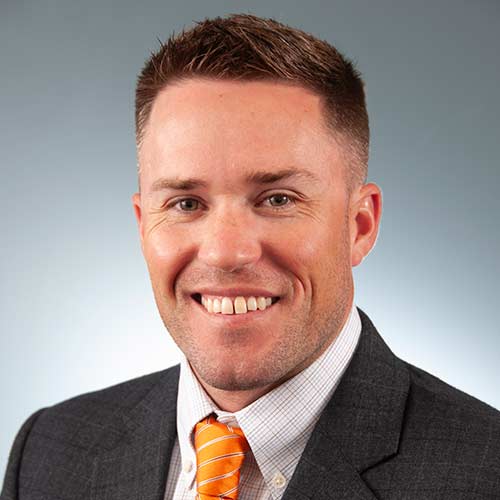 a man wearing a suit and tie smiling at the camera