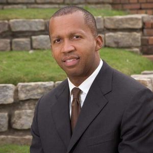 Bryan Stevenson In A Suit Standing In Front Of A Brick Wall