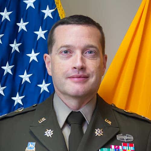 a man wearing a suit and tie smiling at the camera