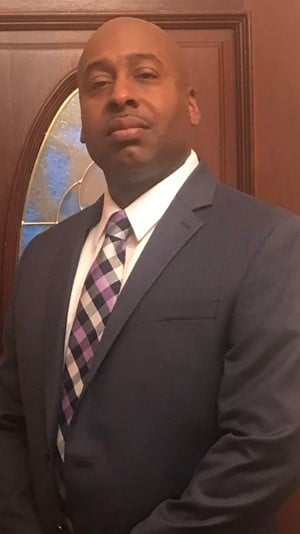a man wearing a suit and tie smiling at the camera