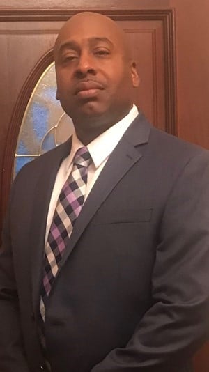 a man wearing a suit and tie smiling at the camera