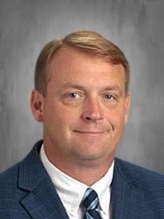 a man wearing a suit and tie smiling at the camera