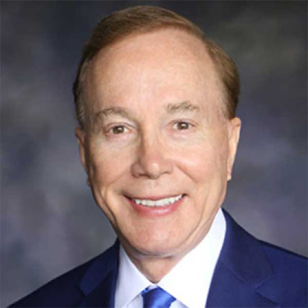 a man wearing a suit and tie smiling at the camera