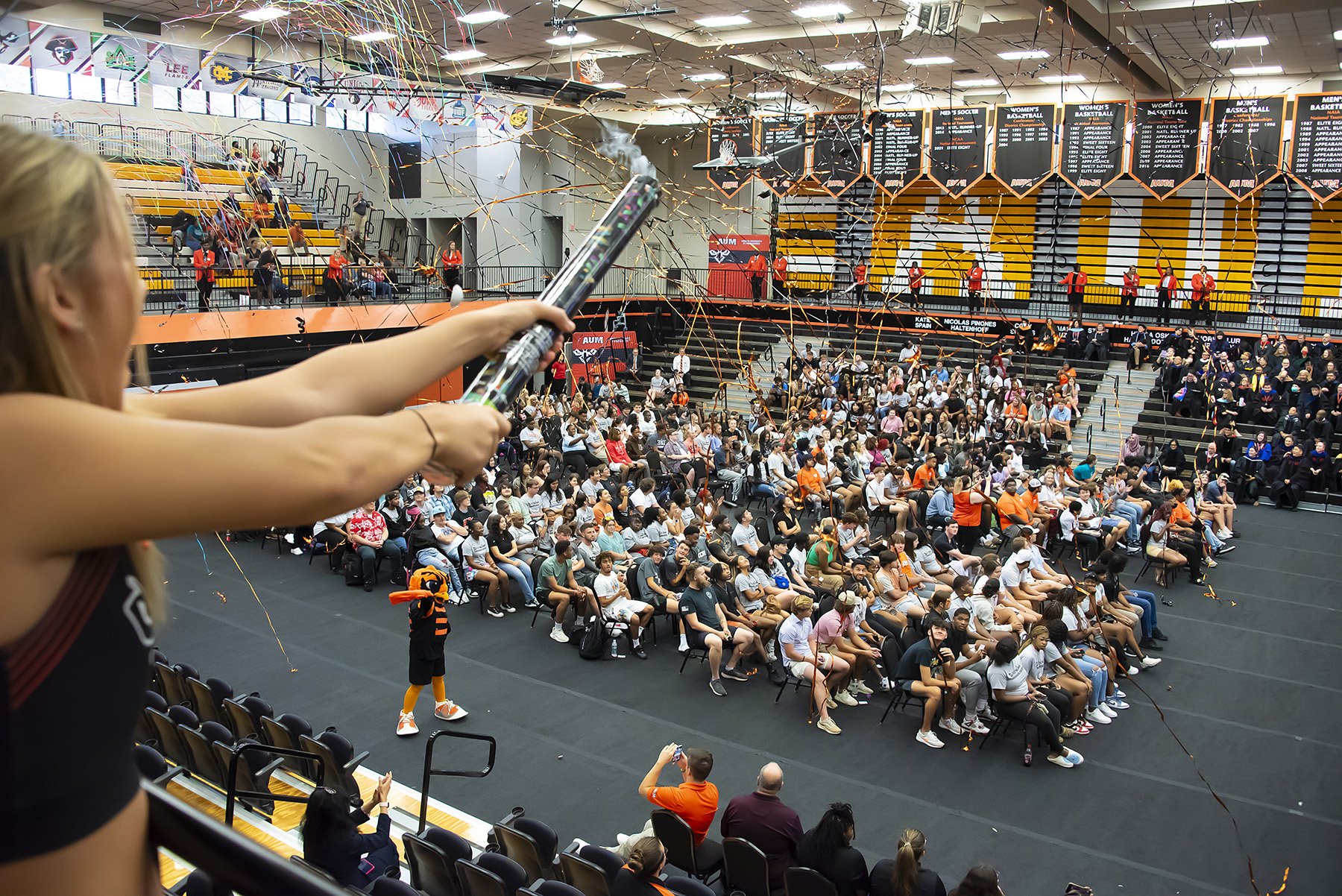 A cheerleader fires a confetti cannon at AUM's New Student Convocation
