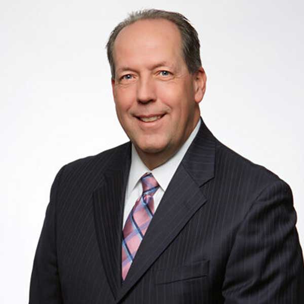 a man wearing a suit and tie smiling at the camera