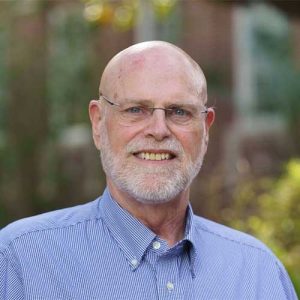 a man wearing glasses and smiling at the camera