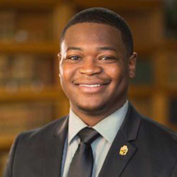 a man wearing a suit and tie smiling at the camera