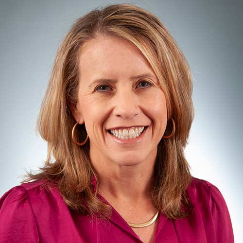 a woman wearing a purple shirt and smiling at the camera