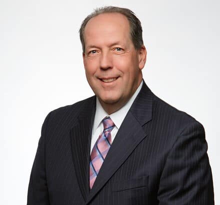 a man wearing a suit and tie smiling at the camera