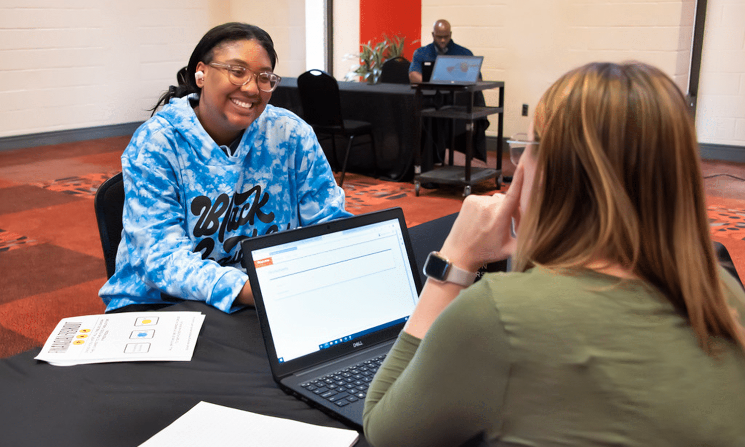 Dana Howze et al. sitting at a table using a laptop computer