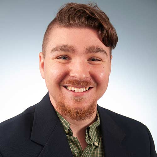 a man wearing a suit and tie smiling at the camera