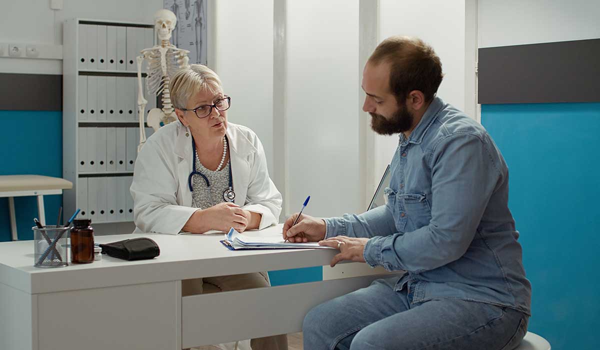 a man and a woman sitting at a desk looking at a laptop