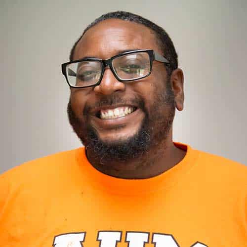 a man wearing glasses and smiling at the camera