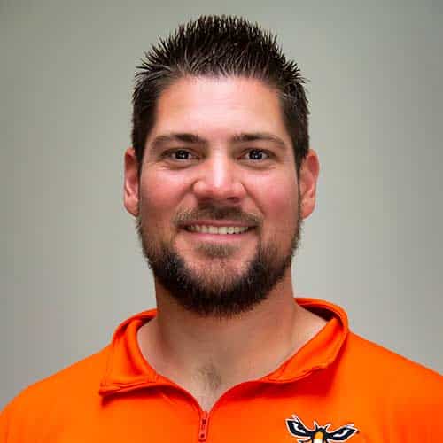 a man in orange shirt smiling and looking at the camera