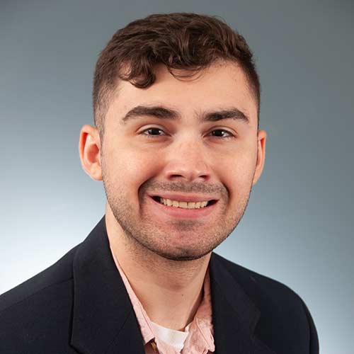 a man wearing a suit and tie smiling at the camera
