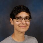 a person wearing glasses and smiling at the camera