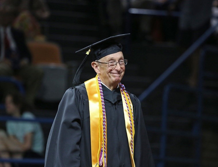 George Brady stands in graduation regalia.