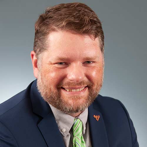 a man wearing a suit and tie smiling and looking at the camera