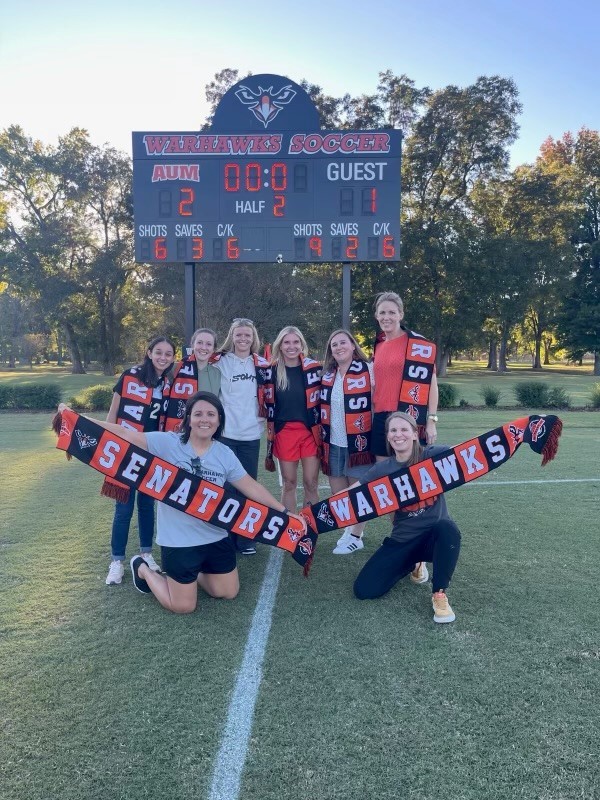 Women's Soccer holding banners from throughout the years to cheer on the team,