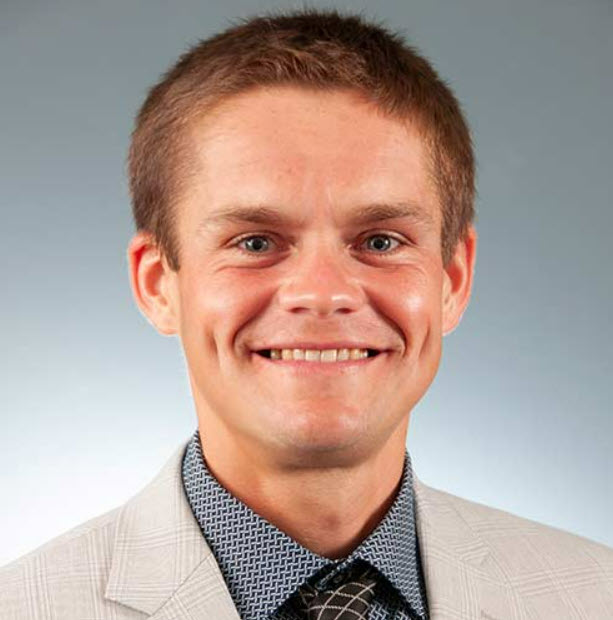 a man wearing a suit and tie smiling at the camera