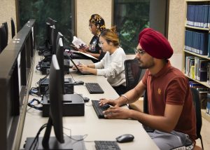 a group of people sitting at a table using a laptop computer