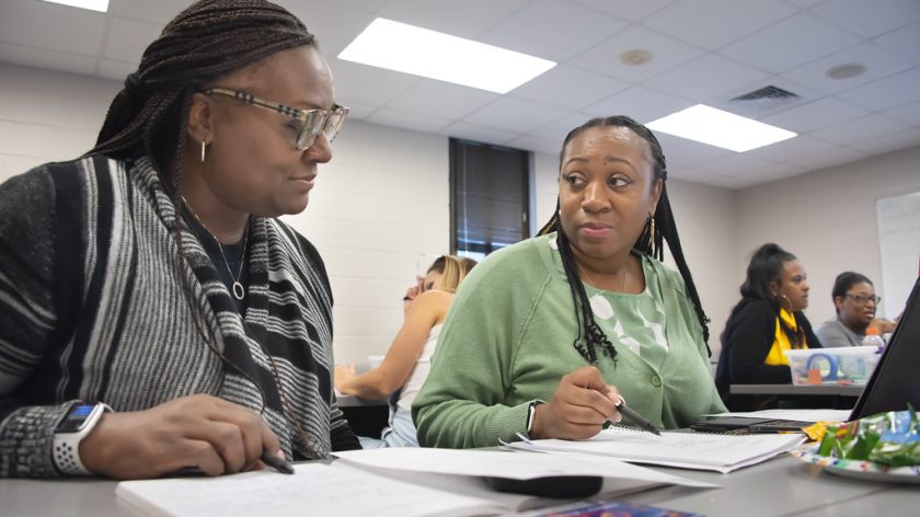 Two Female Educators Discuss Notes While Seated At A Table During A Workshop On The Auburn University At Montgomery Campus.