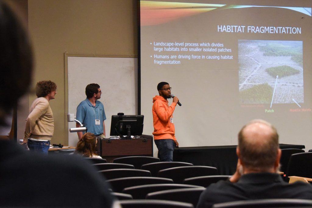 A Student Explains His Team's Work During The College Of Sciences Student Research Symposium