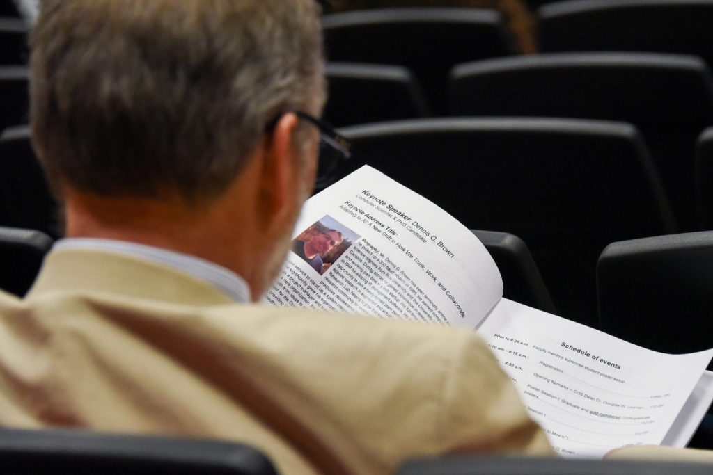 An Auburn University At Montgomery Staff Member Looks At The Event Program At The College Of Sciences Research Symposium.