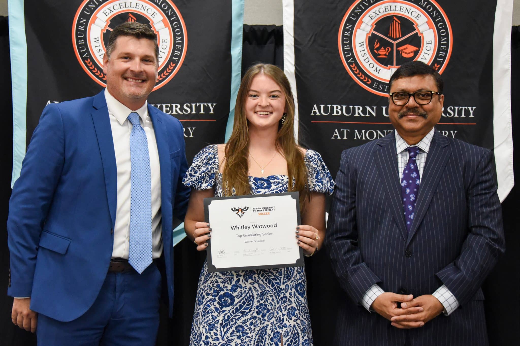 Whitley Watwood receiving an award at Auburn University at Montgomery event, standing with two men.