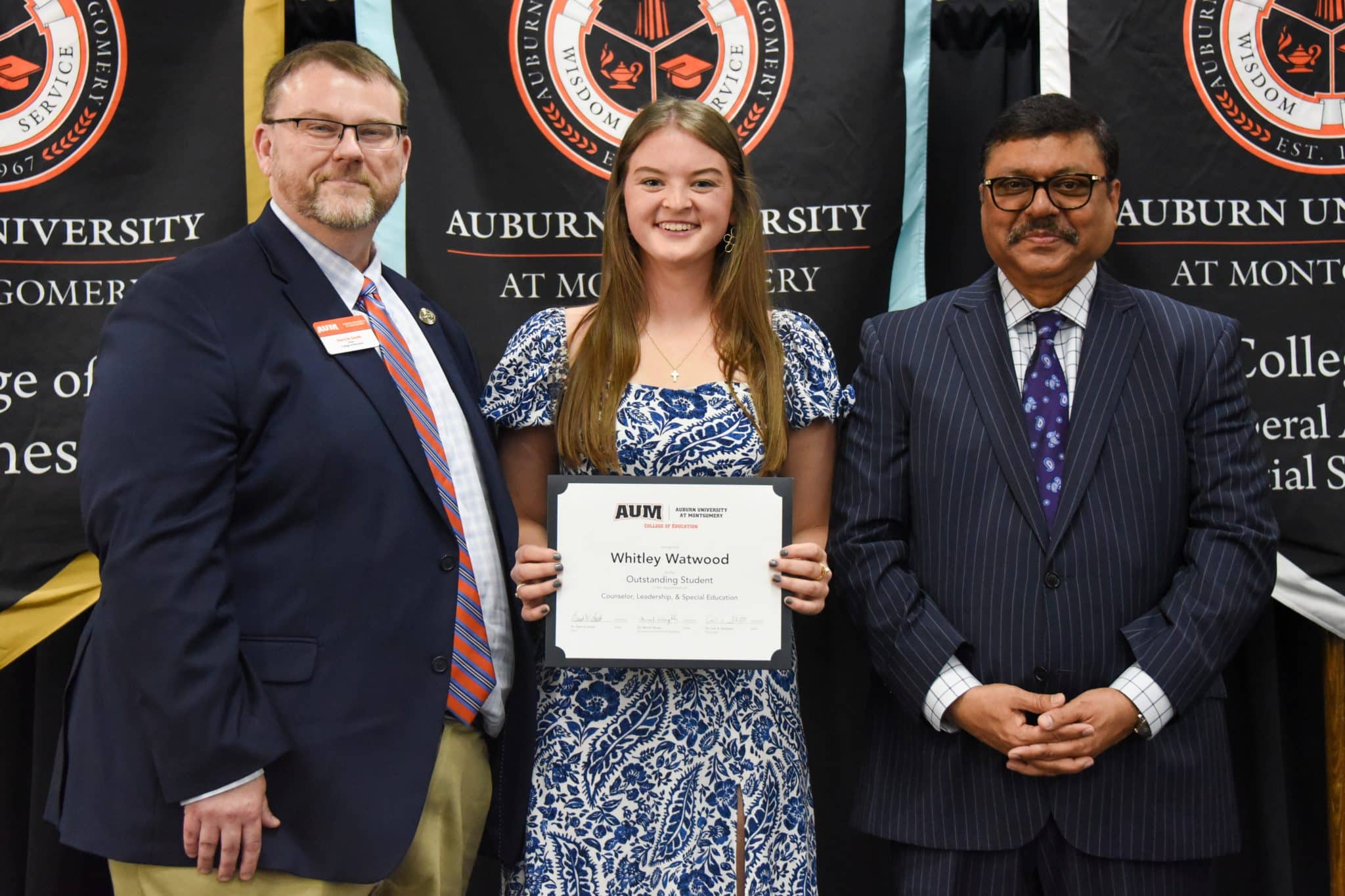Whitley Watwood receiving an award at Auburn University at Montgomery event, standing with two men.