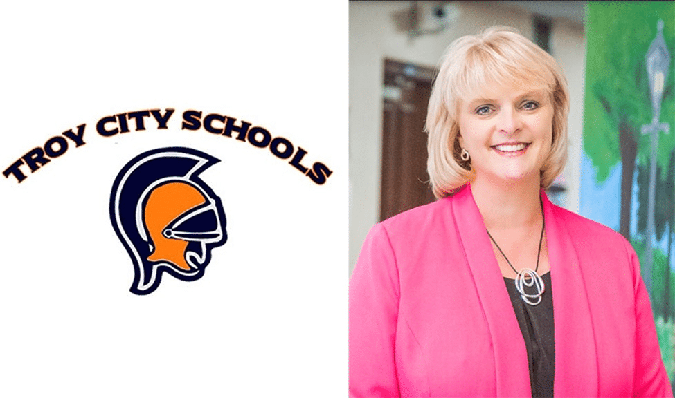 Troy City Schools logo and a woman smiling in a bright pink blazer.